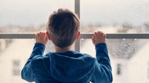 Child looking out of window (posed by model)