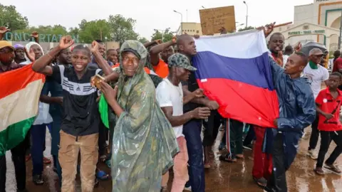 EPA Supporters of the coup outside the National Assembly showing people holding Niger and Russian flags - Thursday 27 July 2023