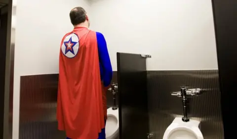 Shutterstock A superhero uses a urinal