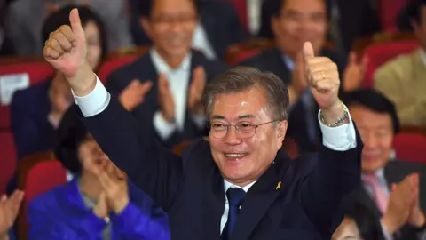 AFP South Korean presidential candidate Moon Jae-in (C) of the Democratic Party reacts as he watches screens showing the result of exit polls of the presidential election at a hall of the National Assembly in Seoul on May 9, 2017.