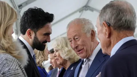 Getty Images King Charles III, standing next to Queen Camilla, interacts with New York City Mayor Zohran Mamdani during a state visit by King Charles III and Queen Camilla on April 29, 2026, in New York City.