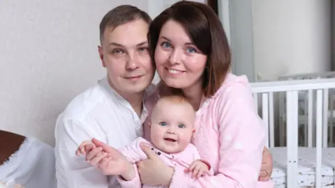 Taisiia Family photo of Taisiia and her husband holding their baby