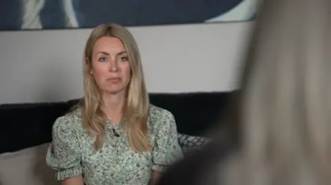 Image shows BBC journalist Hayley Hassall listening to the woman, who is seen from the back and is out of focus. 