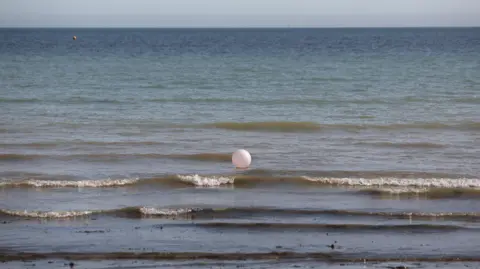 A loose beach ball floats along the sea shore in Worthing, Wedt Sussex