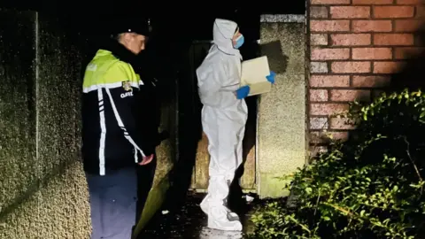 Outside a property a Gardaí and a forensic officer continue the search into the night.