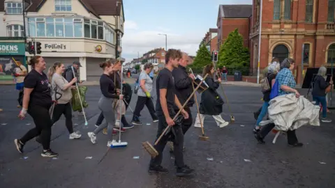 Ian Forsyth/Getty People of all ages with brushes walking along a main street in Middlesbrough