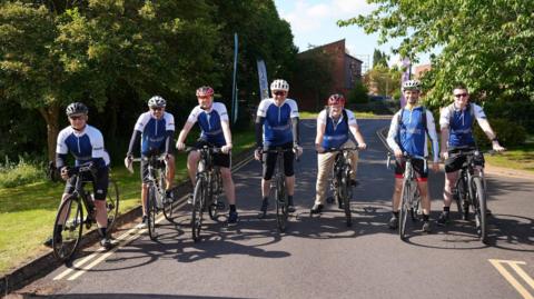 Seven cyclists from St Margaret's Hospice lined up in a row