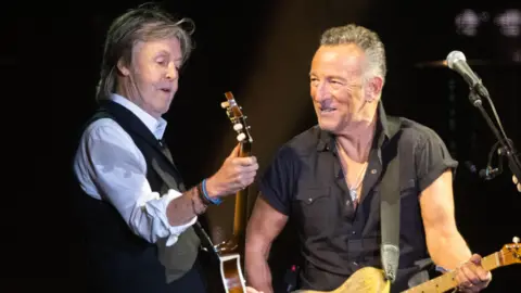 Getty Images Paul McCartney and Bruce Springsteen play their guitars as they perform together on a Glastonbury stage