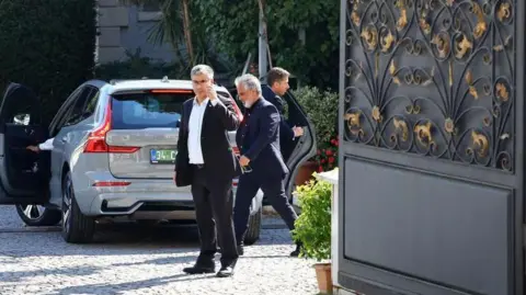 A staff member guards the gate of the Iranian Consulate as a European delegation arrives in a car ahead of nuclear talks, in Istanbul, Turkey, 25 July 2025