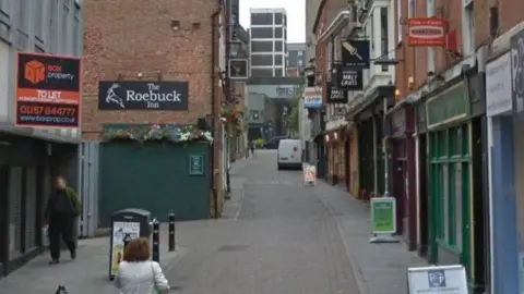 A narrow street with bars either side.
