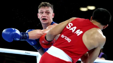 Getty Images Sonny Kerr of Team Scotland punches Marion Ah Tong of Team Samoa in the Men's 70kg Quarter-Final match on day six of the Glasgow 2026 Commonwealth Games at SEC Centre in Glasgow, Scotland.