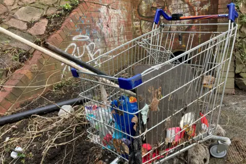 On the side of the waterway a discarded shopping trolly has been found with an assortment of rubbish, including old plastic pipes and food wrappers. 