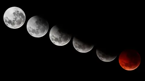 Getty Images A composite image showing different stages of the 2010 solstice total lunar eclipse. The sequence captures the Moon gradually moving into Earth's shadow, transitioning from a bright full Moon to partial darkness, and finally turning a deep red hue during totality. The background is a black sky.