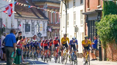 SWpix.com Cyclists ride through the streets of Framlingham. Spectators cheer them on from the pavements. Bunting is hung across the buildings either side of the road.