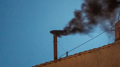 Black smoke is seen from the chimney of the Sistine Chapel