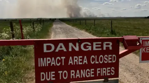 A red sign on Salisbury Plain's military training area starting "DANGER, IMPACT AREA CLOSED DUE TO RANGE FIRES".