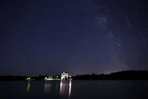 AFP A meteor streaks as satellites cross the night sky over a monastery