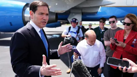 US Secretary of State Marco Rubio speaks to the press in front of a plane