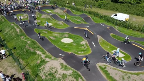 Connor Bennett/BBC An aerial view of a track with cyclists on it.