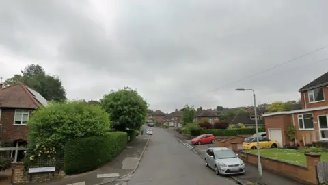 Google A residential street with green trees and a number of cars on either side