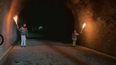 Lit torches being held in a disused railway tunnel in Heathfield in West Sussex