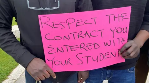 Students holding pink protest sign