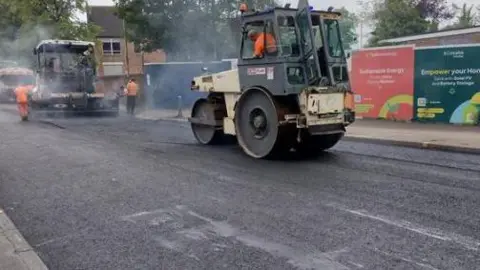 Roads being resurfaced by two resurfacing trucks on a road