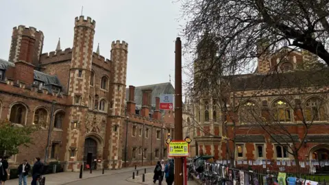 Steve Hubbard/BBC View of St John's Street in Cambridge showing a street light without a lantern at the top. University buildings can be seen in the background and there are pedestrians on the pavements