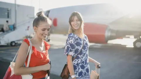 Getty Images Young couple are boarding their plane at the airport to go on holiday