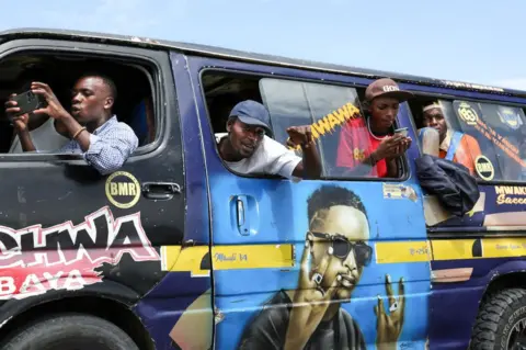 TONY KARUMBA/AFP People take photos out of the windows of a minibus in Naivasha.