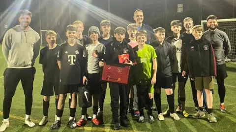 Alfreton Town Juniors Ivan pictured with the rest of the Alfreton Town Juniors U13 all stars team, posing with a signed shirt and box of malteasers.