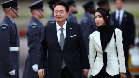 Getty Images South Korea's President Yoon Suk Yeol and his wife Kim Keon Hee disembark from an aircraft after landing at London Stansted Airport on November 20, 2023