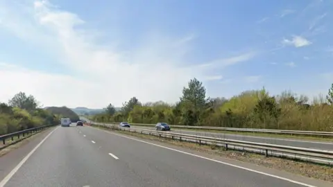 A Google Street View of the A303, a dual carriageway weaving into hills in the distance.