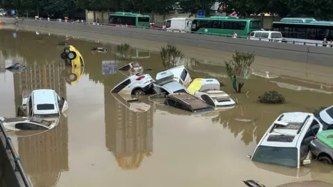 Getty Images Cars sit in floodwaters after heavy rains hit the city of Zhengzhou in China's central Henan province on July 21, 2021.