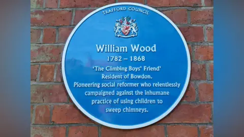 Trafford Council A photo of a Trafford Council blue plaque on a red brick wall which says: William Wood, 1782 - 1868, 'The Climbing Boys' Friend'. Resident of Bowdon. Pioneering social reformer who relentlessly campaigned against the inhumane practice of using children to sweep chimneys. 