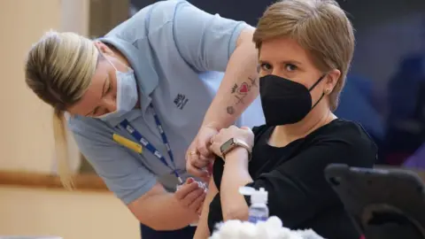 Getty Images First Minister of Scotland Nicola Sturgeon receives a Covid booster jab and a separate flu jab from healthcare support worker vaccinato