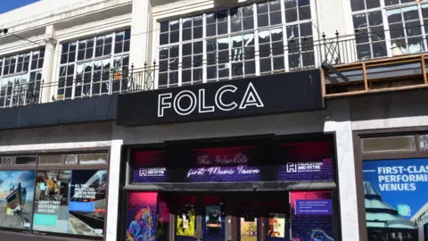 A black building called Folca with billboards up.