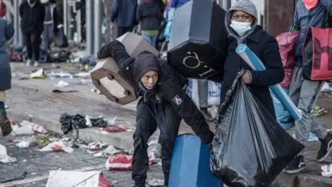 Looters take away few items left to grab in a vandalised mall in Vosloorus, on July 14, 2021