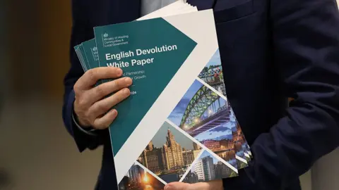 Close up of a man holding the English Devolution White Paper documents