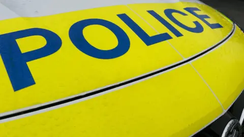 The front of a Devon and Cornwall Police vehicle with a fluorescent yellow bonnet and the word Police in blue.