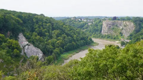 A view of Avon Gorge, taken from the Clifton Suspension Bridge. There are high cliffs on either side, with the River Avon running through the middle. 