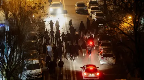 Reuters A nightime street in Tehran with people gathered in the road around cars