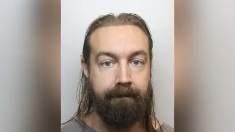 Stuart Trentham police custody image. He has a beard and long hair.