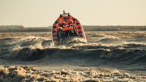 Humber Rescue The sun is out but the waves coming in have sent a lifeboat pointing upwards to the sky as it heads out.