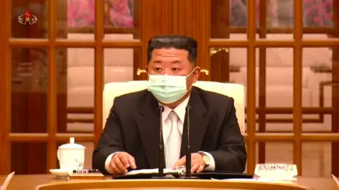 KCTV / AFP Kim Jong-un wearing a face mask at a government meeting