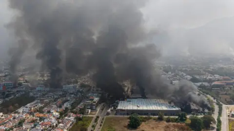 An aerial photograph shows plumes of smoke over Puerto Vallarta after the killing of Nemesio Oseguera, known as El Mencho, was killed on 22 February 2026.