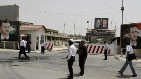 Entrance to a prison with several people walking in front of it