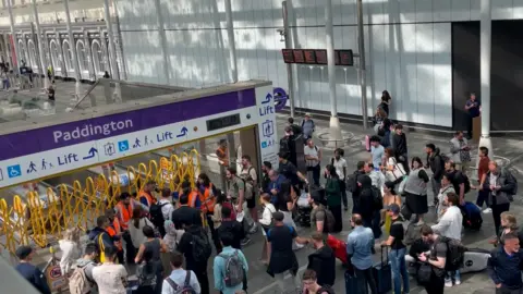 PA Media Crowd of people with luggage entering Paddington station via the Elizabeth line entrance.