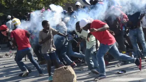 AFP/Getty Images A tear gas canisters hits protesters in Port-au-Prince, Haiti. Photo: 13 February 2019