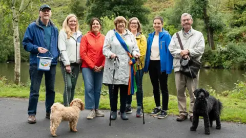 Charlie Swinbourne Photography Sheila with six members of Ilkley Good Neighbours charity, and two dogs, walking at the tarn